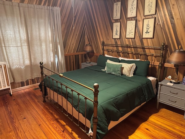 bedroom with wood finished floors and wood walls