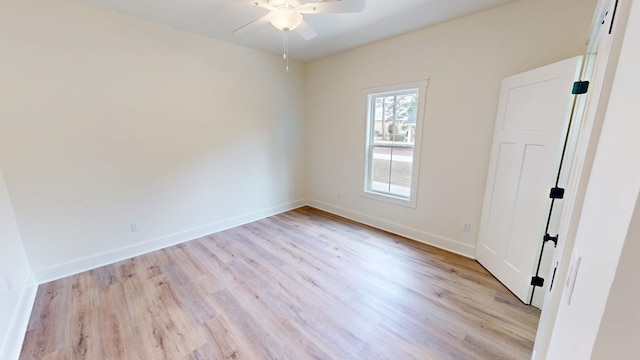 spare room with ceiling fan, light wood-style flooring, and baseboards