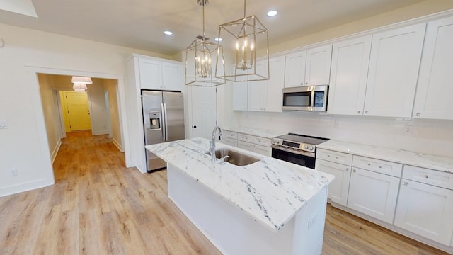 kitchen with a center island with sink, white cabinetry, stainless steel appliances, and a sink