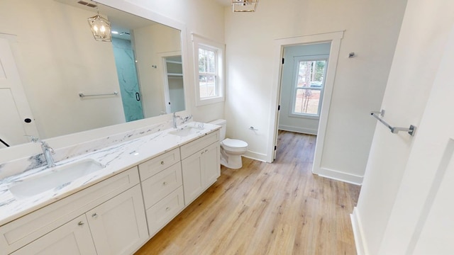 bathroom with double vanity, baseboards, a sink, and wood finished floors