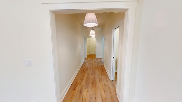 hall with light wood-style floors and baseboards