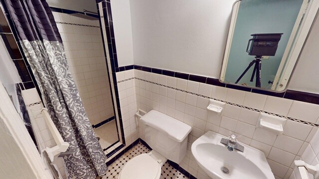 610 Partridge Dr, Thomasville, GA 31792 - bathroom featuring a sink, a stall shower, tile walls, wainscoting, and toilet