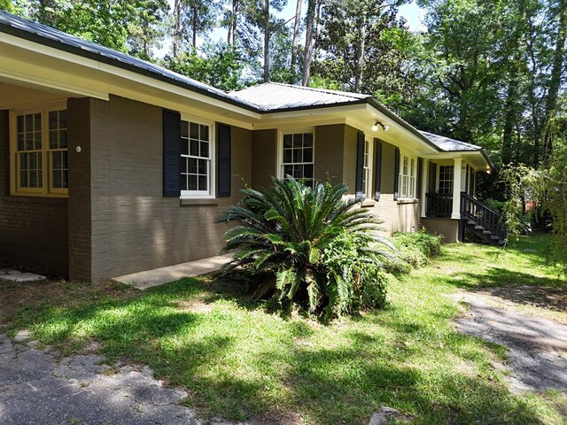 610 Partridge Dr, Thomasville, GA 31792 - view of side of home with brick siding, a lawn, and metal roof