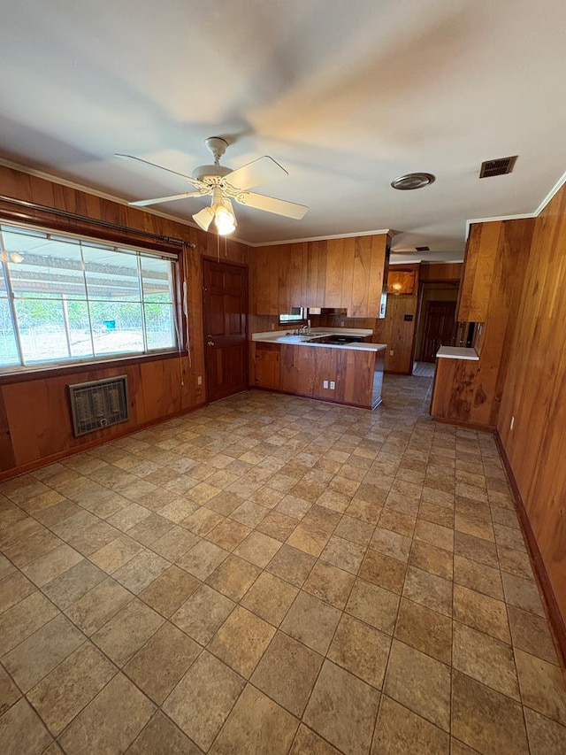 kitchen with visible vents, brown cabinets, wooden walls, and a peninsula