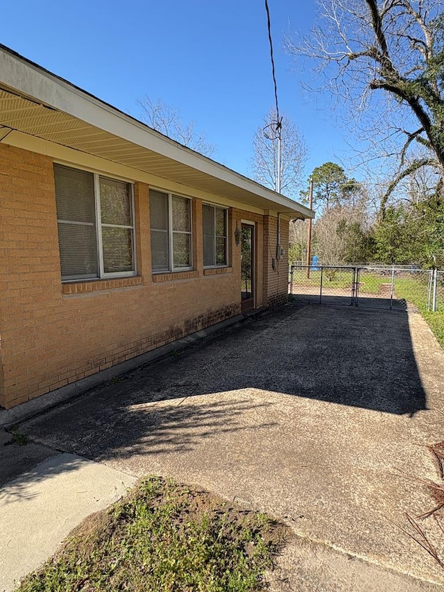 exterior space featuring a gate, fence, and brick siding