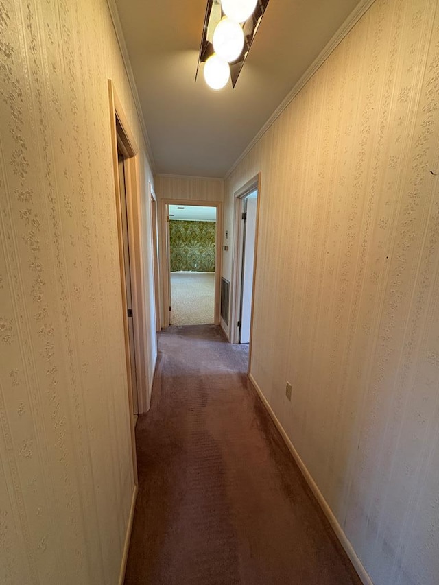 hall featuring carpet flooring, baseboards, and ornamental molding