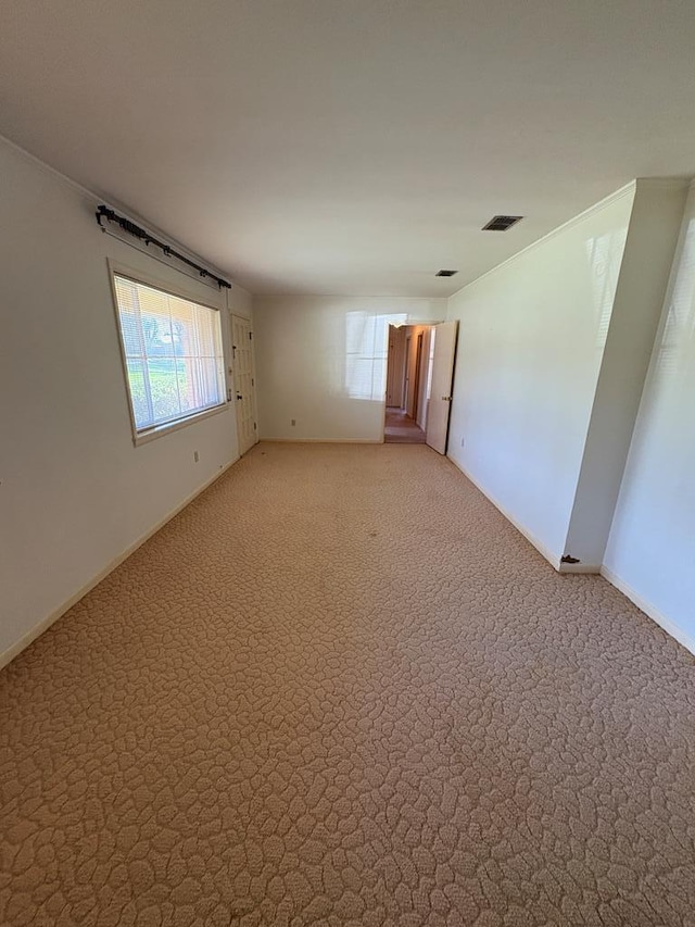 empty room featuring visible vents, light colored carpet, and baseboards