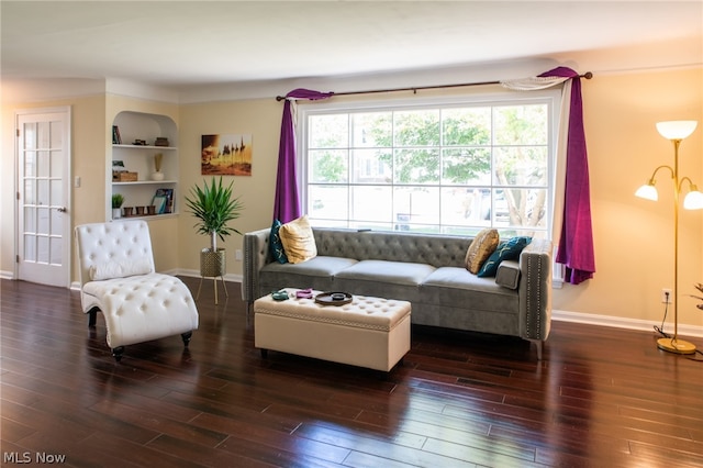 living room featuring dark wood-type flooring and built in shelves