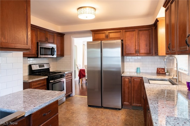 kitchen featuring stainless steel appliances, sink, backsplash, and light wood-type flooring