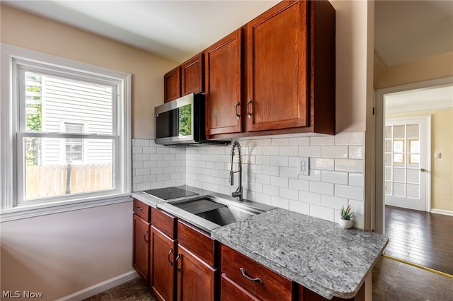 kitchen with dark hardwood / wood-style flooring, light stone counters, black electric cooktop, sink, and tasteful backsplash