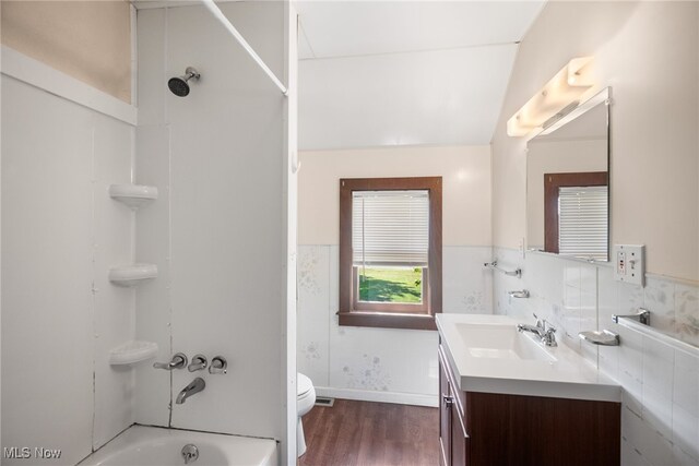 full bathroom featuring hardwood / wood-style flooring, bathtub / shower combination, toilet, lofted ceiling, and vanity