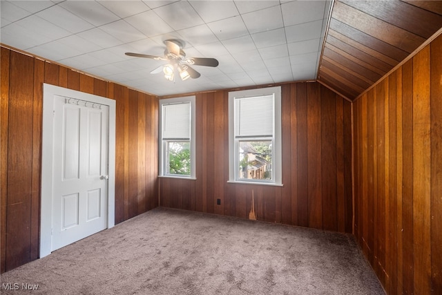 bonus room with lofted ceiling, wood walls, ceiling fan, and carpet floors