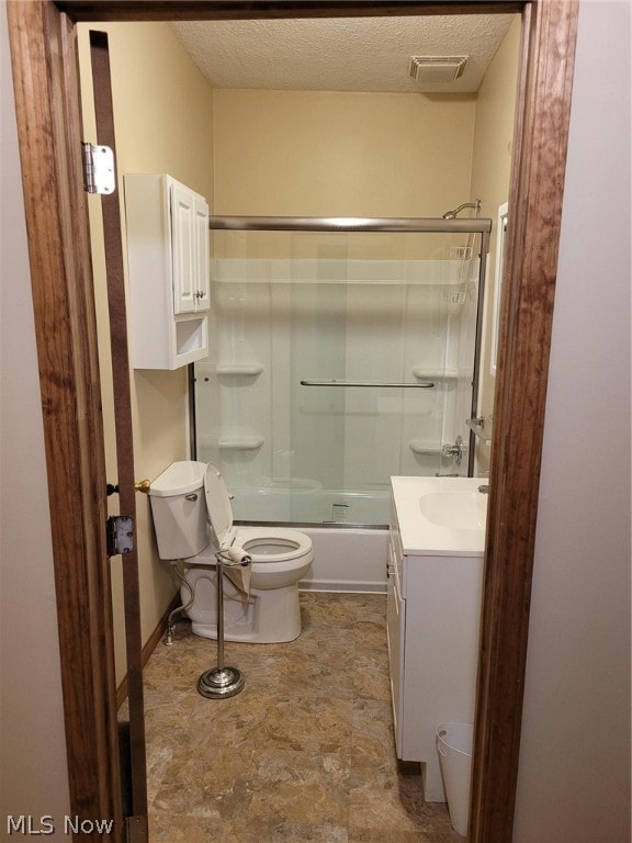 full bathroom featuring tile patterned floors, a textured ceiling, vanity, combined bath / shower with glass door, and toilet