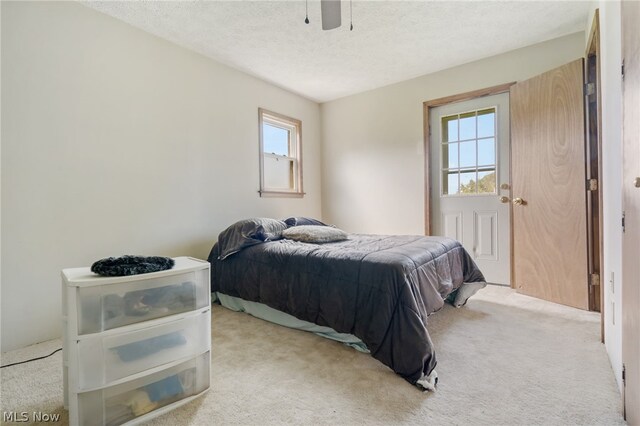 carpeted bedroom with ceiling fan and a textured ceiling