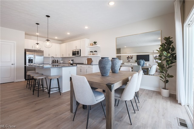 dining space with light hardwood / wood-style flooring and sink