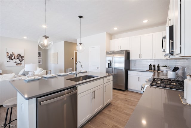 kitchen featuring sink, light wood-type flooring, stainless steel appliances, and a kitchen island with sink