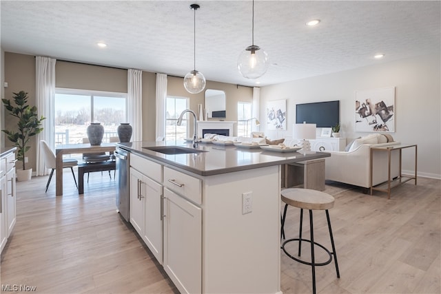 kitchen with white cabinetry, light hardwood / wood-style floors, sink, and an island with sink