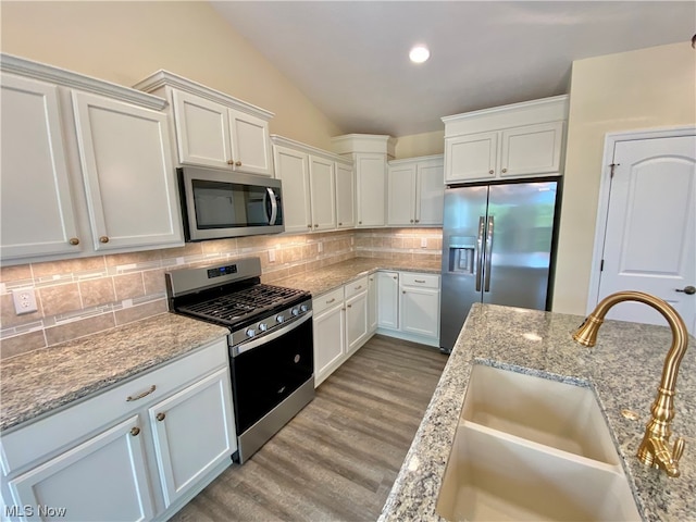 kitchen with white cabinets, decorative backsplash, stainless steel appliances, and a sink