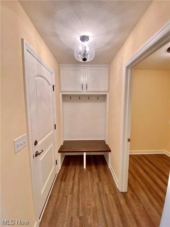 mudroom with a textured ceiling, baseboards, and wood finished floors