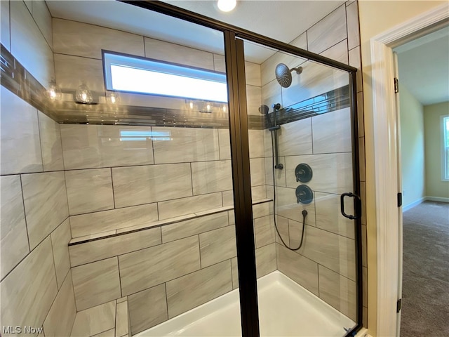 full bath with a wealth of natural light, a shower stall, and baseboards