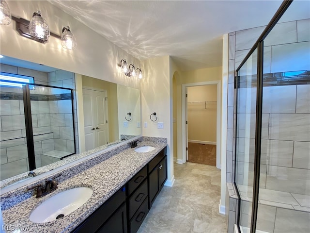 full bathroom with a stall shower, a walk in closet, a sink, and double vanity