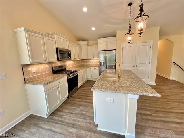 kitchen with arched walkways, wood finished floors, stainless steel appliances, white cabinetry, and a sink