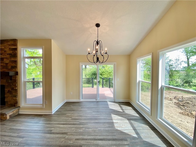 unfurnished dining area featuring hardwood / wood-style flooring, plenty of natural light, a chandelier, and a textured ceiling