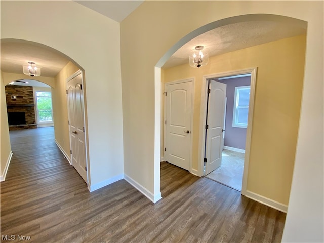 corridor with a textured ceiling and dark hardwood / wood-style flooring