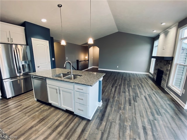 kitchen featuring sink, white cabinets, appliances with stainless steel finishes, decorative light fixtures, and dark stone countertops