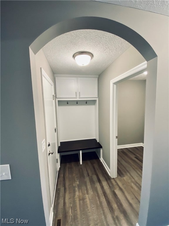 hallway with a textured ceiling and dark hardwood / wood-style flooring