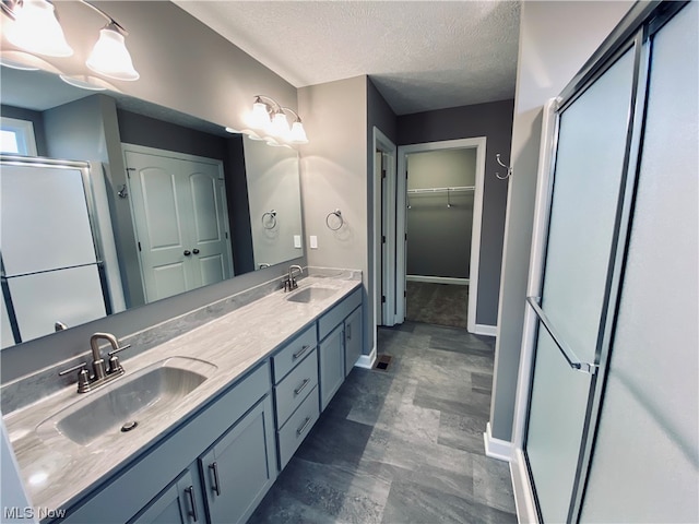 bathroom featuring a textured ceiling, vanity, and a shower with shower door