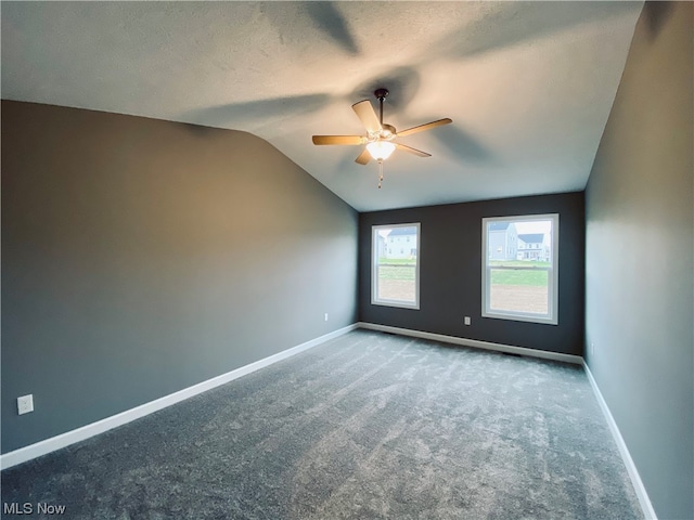 empty room featuring lofted ceiling, carpet flooring, and baseboards