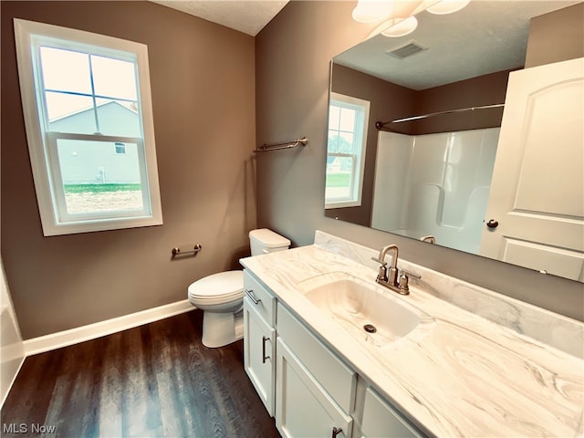 bathroom with a textured ceiling, wood-type flooring, vanity, and toilet