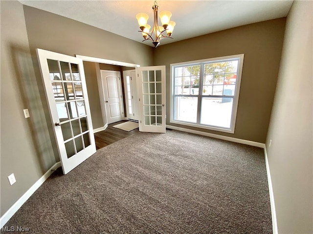 carpeted spare room with french doors, baseboards, and an inviting chandelier