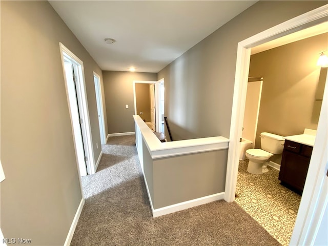 hall with carpet, baseboards, and an upstairs landing