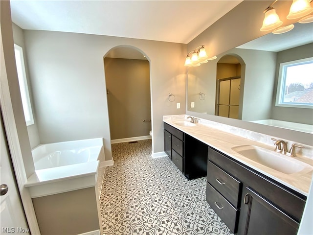 full bath featuring double vanity, baseboards, a sink, and a bath