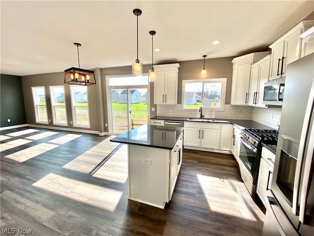 kitchen featuring stainless steel appliances, a center island, hanging light fixtures, and dark wood-type flooring