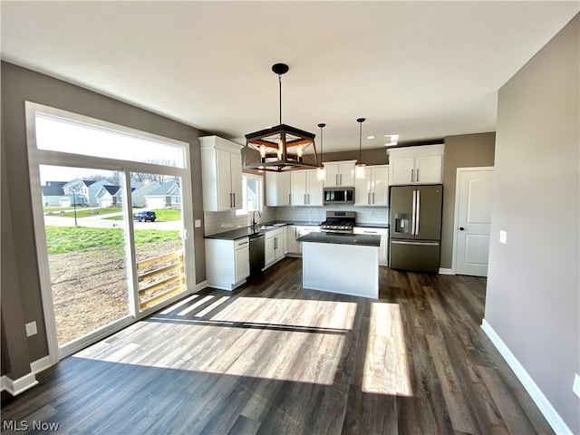 kitchen with dark wood-style floors, decorative backsplash, appliances with stainless steel finishes, white cabinets, and a sink