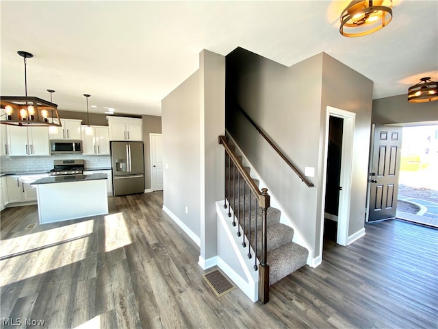 interior space with appliances with stainless steel finishes, white cabinetry, dark hardwood / wood-style floors, and decorative light fixtures