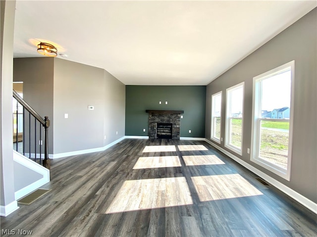 unfurnished living room featuring visible vents, stairway, a stone fireplace, wood finished floors, and baseboards