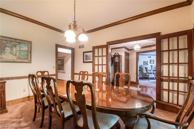 carpeted dining room with french doors, ornamental molding, and an inviting chandelier