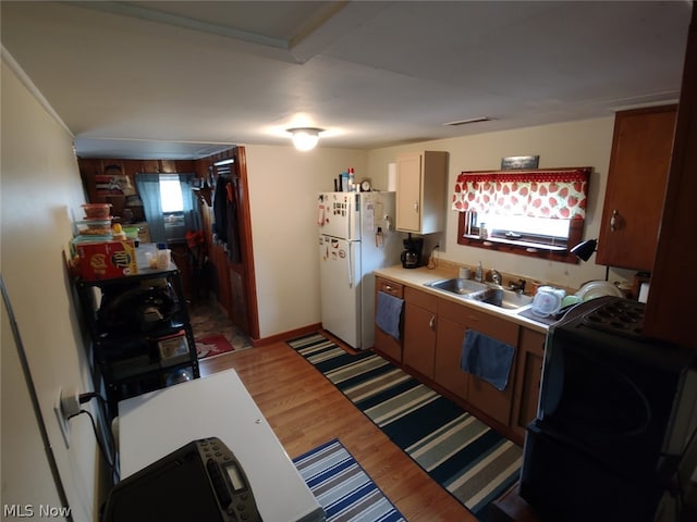 kitchen with white fridge, sink, and light hardwood / wood-style floors