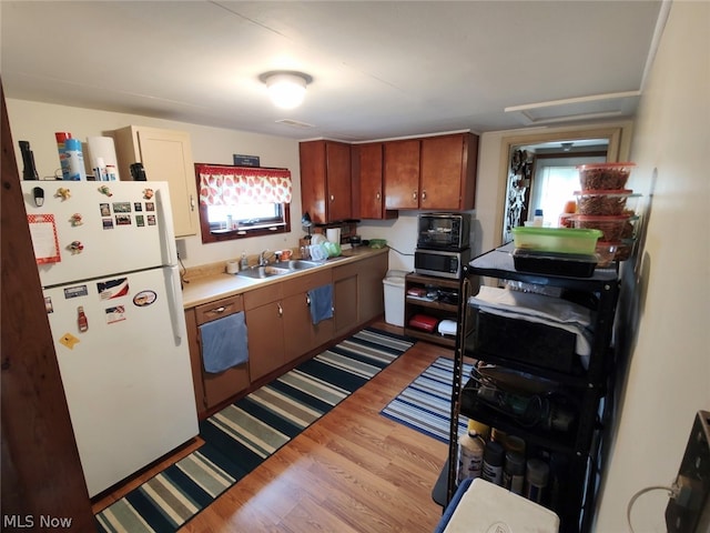 kitchen featuring hardwood / wood-style flooring, sink, and white fridge