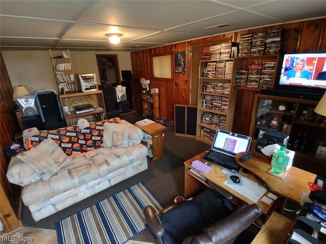 carpeted living room featuring wooden walls