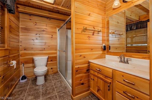 bathroom featuring a shower with shower door, toilet, vanity, and wooden walls