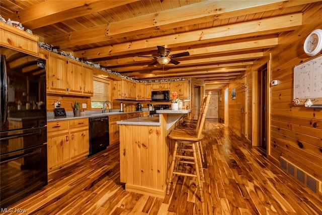 kitchen with dark hardwood / wood-style flooring, black appliances, ceiling fan, a kitchen island, and beam ceiling