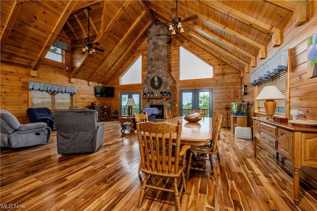 dining room with wooden ceiling, beamed ceiling, wood walls, and ceiling fan