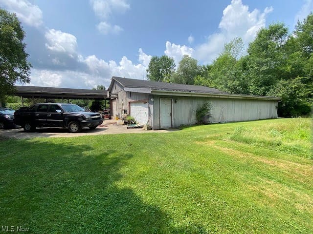 view of side of property featuring a garage and a lawn