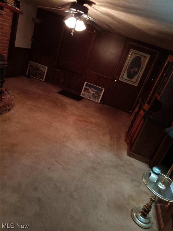 interior space featuring brick wall, ceiling fan, and carpet flooring