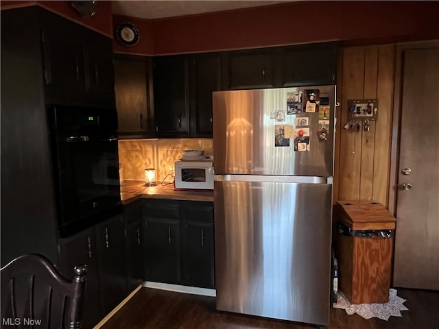 kitchen with tasteful backsplash, oven, dark hardwood / wood-style floors, and stainless steel fridge